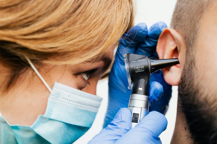 Gros plan d'un médecin effectuant un examen de l'oreille avec un otoscope.